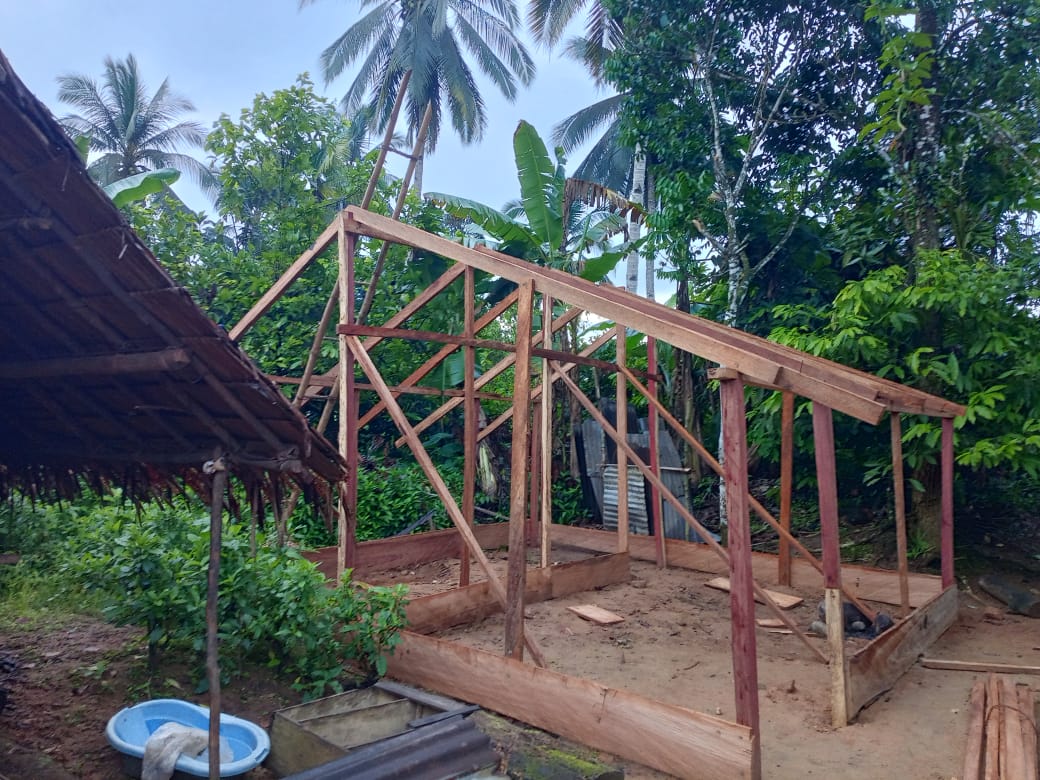 A beneficiary standing inside the poultry house frame